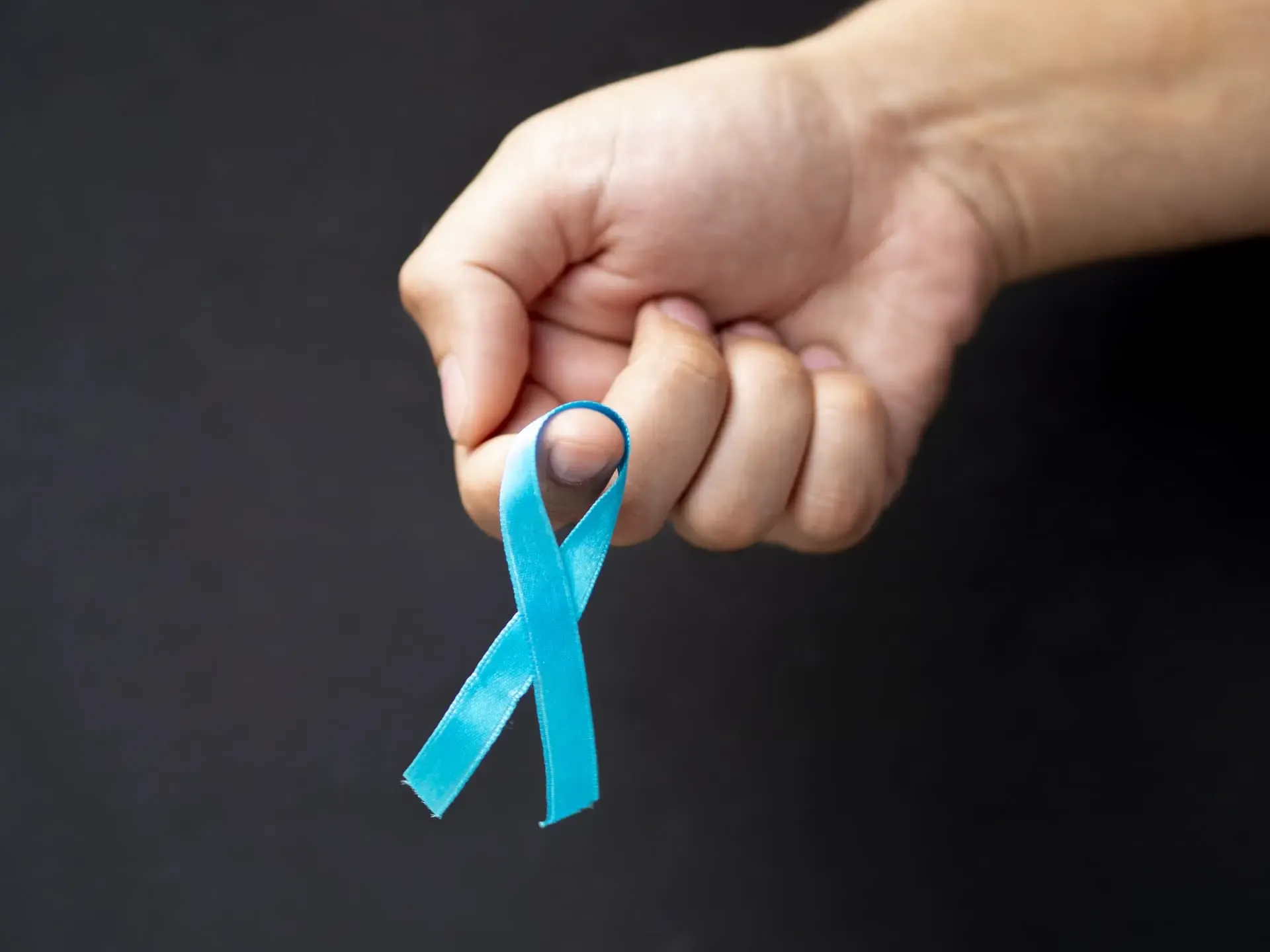 Close Up Man Holding Up Ribbon With Black Background